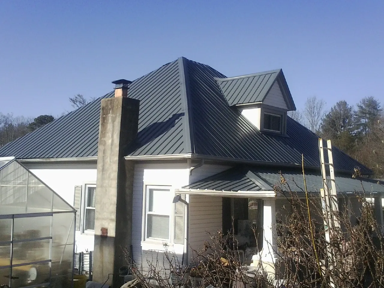 Dark blue standing seam metal roof on a white farmhouse with dormer — Slate & Tile Roof Repair by Roofing Brothers in Ironton
