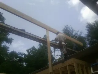 Carpenter setting a ridge beam over a new addition frame — Ice Dam Removal by Roofing Brothers in Ironton