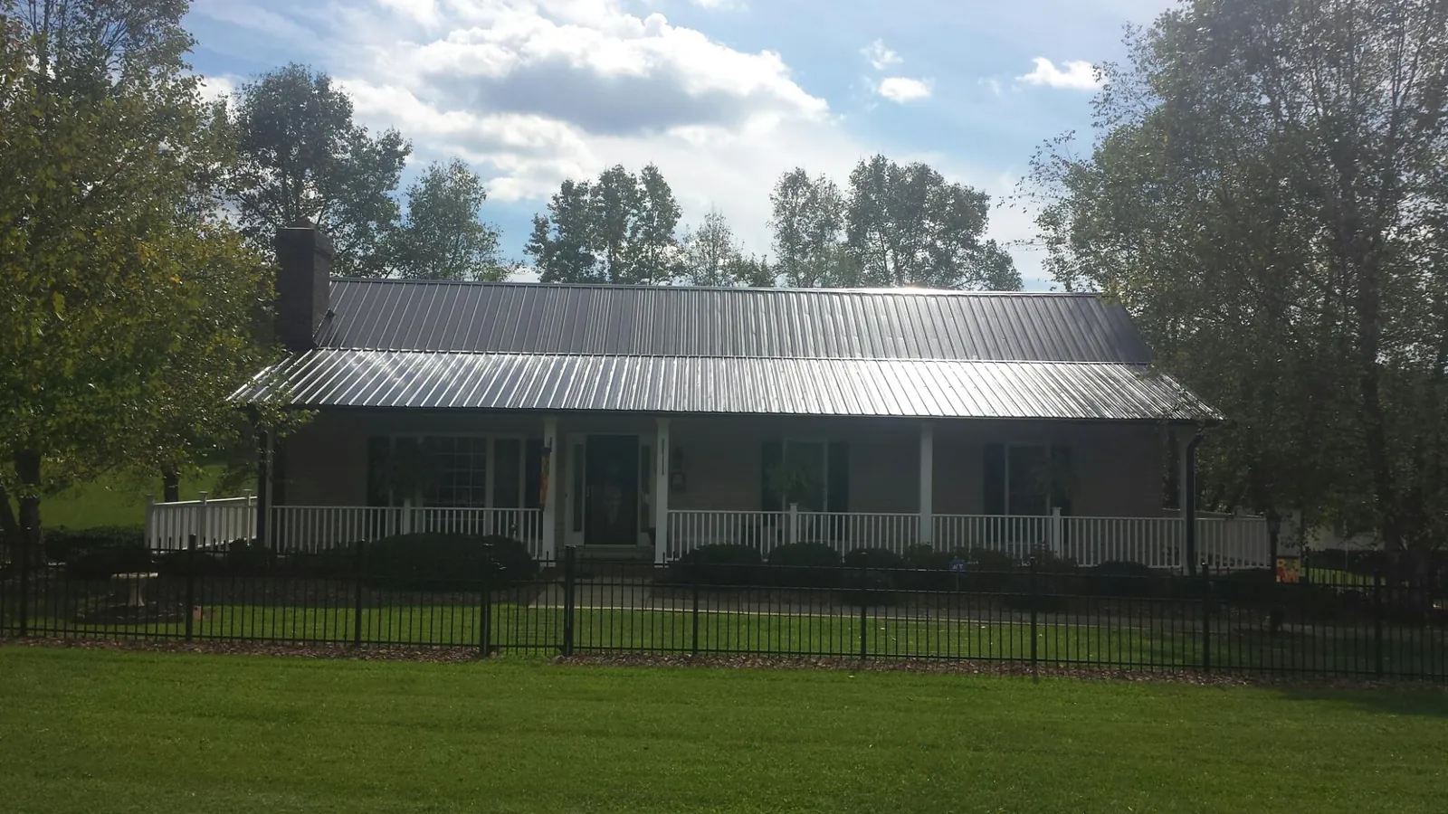 Gray metal roof on a brick ranch with a full width front porch — Gutter Guard Installation work by our crew in Ironton