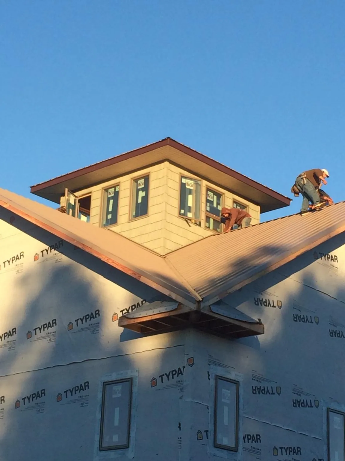 Roofers working around a rooftop cupola on a new metal roof at sunset — Roof Waterproofing in Ironton by Roofing Brothers
